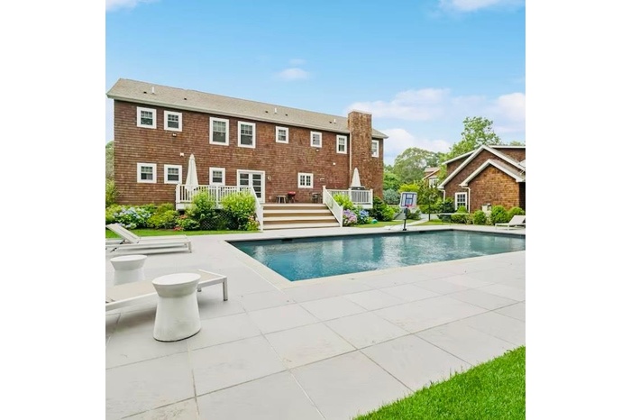 Outdoor pool with a wooden deck and a patio