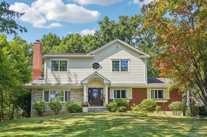 View of front of home with a chimney, a front yard, and stone siding
