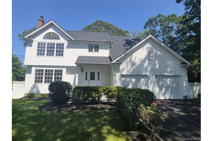 View of front of property featuring a chimney, a garage, driveway, and a shingled roof