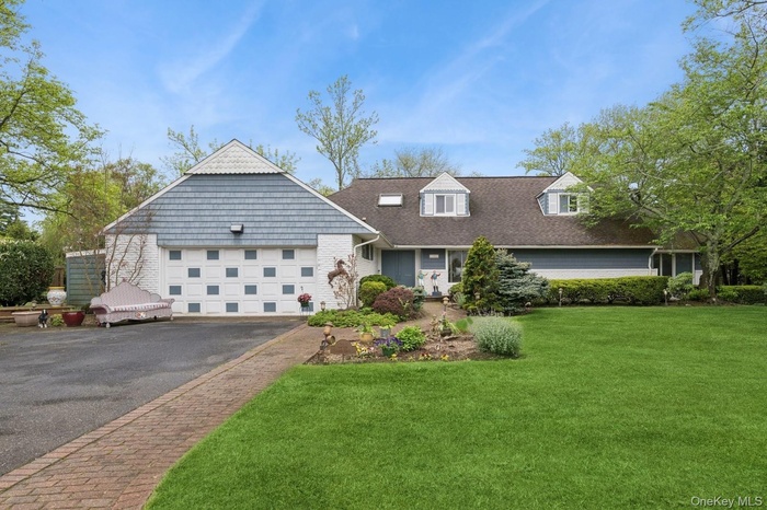 View of front of property featuring driveway, an attached garage, a front yard, and roof with shingles