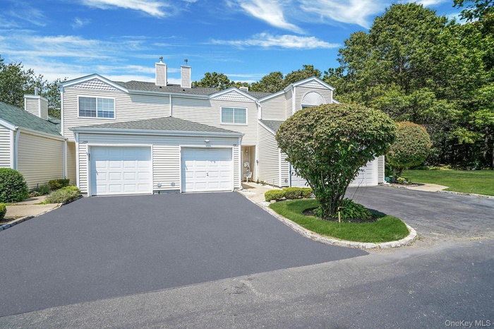 Traditional-style home with asphalt driveway, roof with shingles, an attached garage, and a chimney