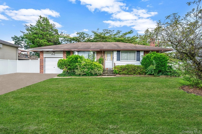 Ranch-style home with a garage, a chimney, brick siding, and driveway