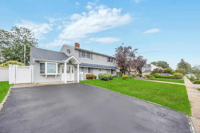 View of front of house featuring driveway, a front lawn, a chimney, a gate, and a shingled roof