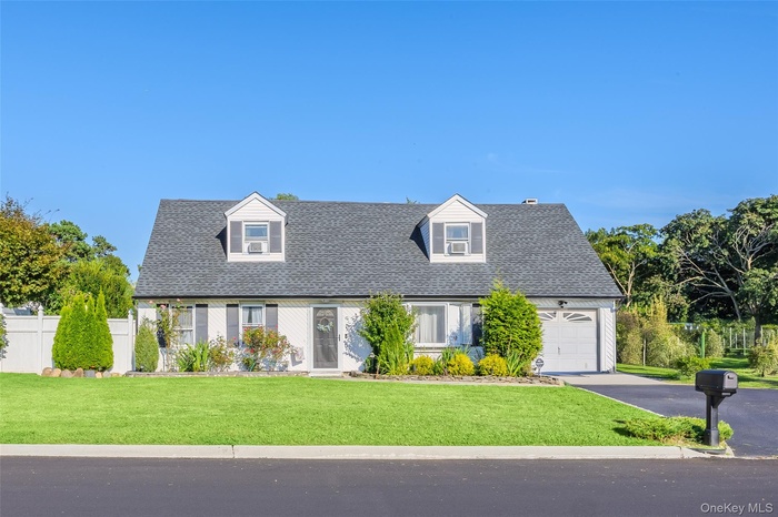 Cape cod home featuring driveway, with an attached garage