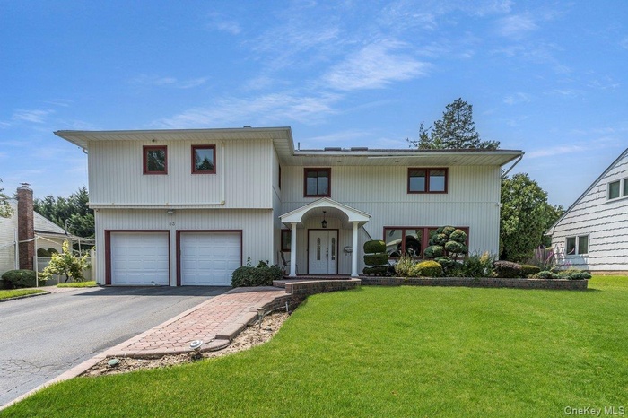 View of front of house featuring a garage, a front yard, and driveway