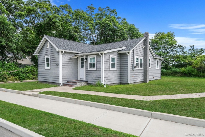 Ranch-style home with a shingled roof, a chimney, and a front yard