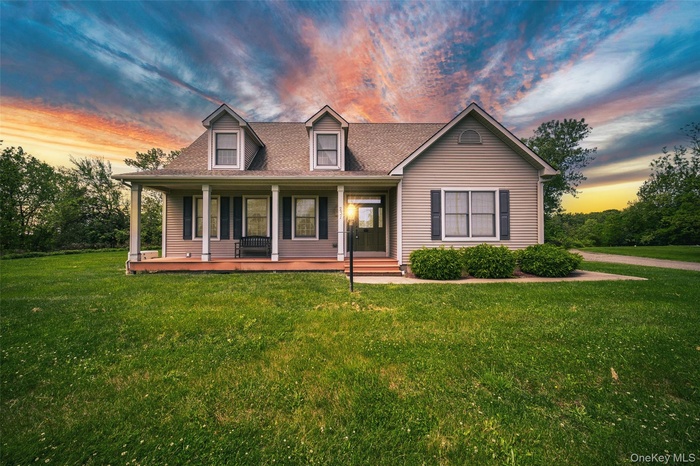 View of front of property with a lawn, covered porch, and roof with shingles