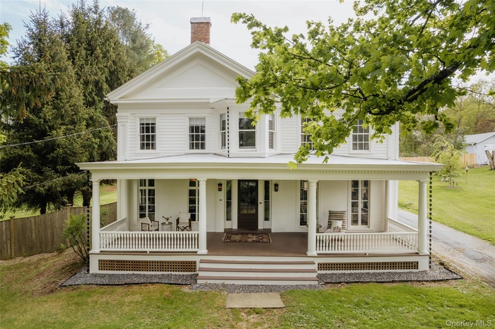 Greek revival house featuring a porch and a chimney