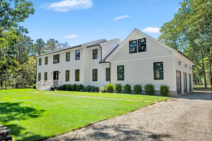 View of front of property featuring gravel driveway, board and batten siding, and a front lawn