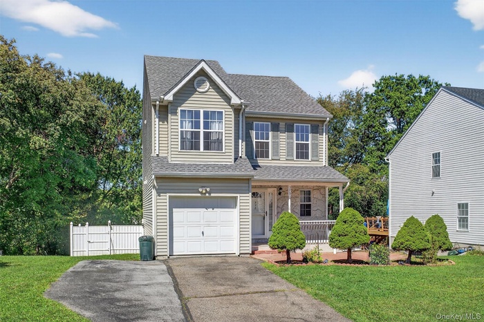 View of front of property with a porch, a shingled roof, a garage, and driveway