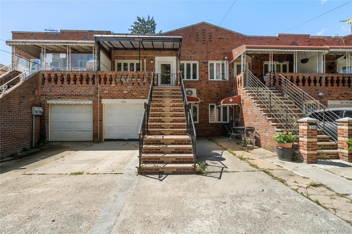 Front of property with stairway, concrete driveway, brick siding, and a garage