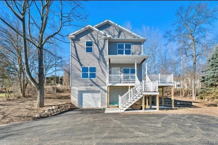 View of front of property featuring stairway, asphalt driveway, an attached garage, and a wooden deck