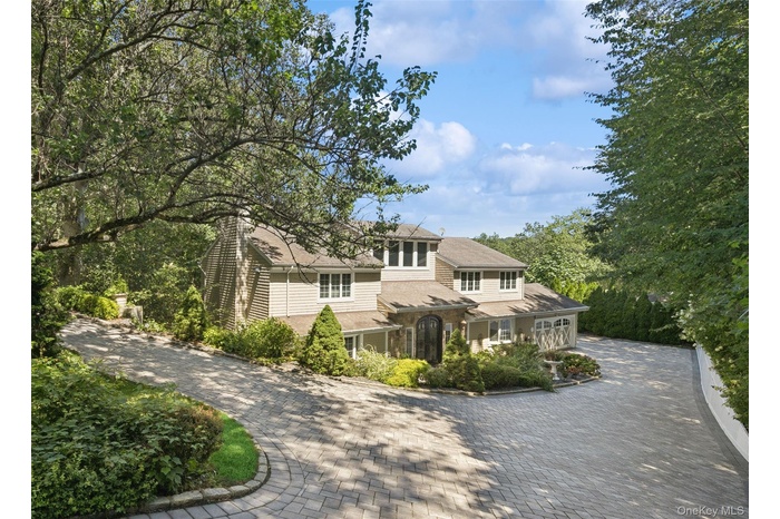 Shingle-style home featuring decorative driveway