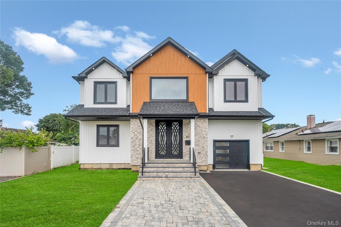 View of front of property with driveway, a garage, and a shingled roof