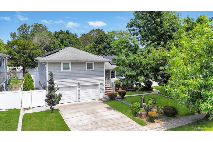 View of front of property featuring driveway, a garage, roof mounted solar panels, and roof with shingles