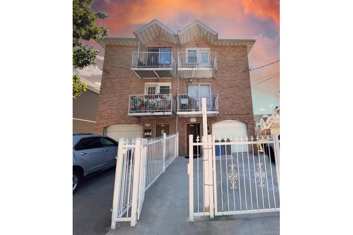 Traditional-style home featuring brick siding, a balcony, a gate, and an attached garage