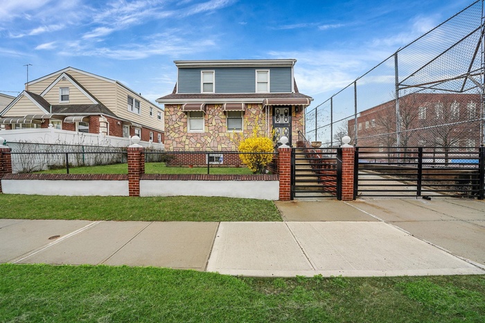 View of front of property with stone siding, a gate, and a fenced front yard