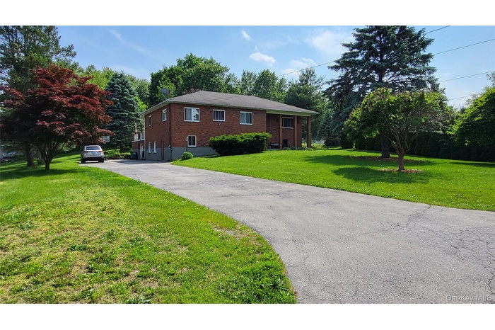 View of the front of the house features a front yard, brick siding, and a driveway