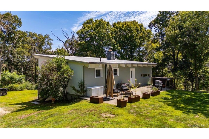 Back of property featuring a chimney, a yard, and a patio