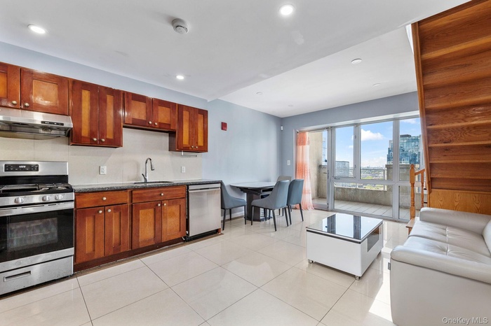 Kitchen with stainless steel appliances, recessed lighting, under cabinet range hood, light tile patterned floors, and a city view