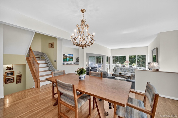 Dining room with a chandelier, light wood-style floors, and stairs