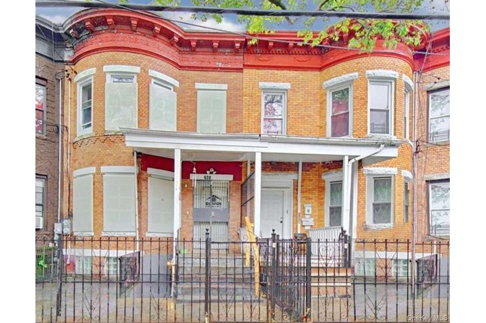 Multi unit property featuring a fenced front yard, a porch, and brick siding