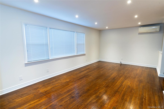 Unfurnished room with dark wood-type flooring, recessed lighting, and a wall mounted air conditioner