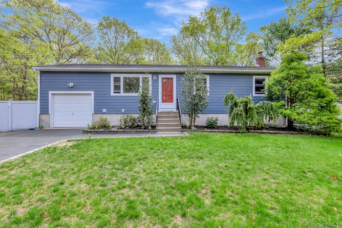 Ranch-style home with a chimney, driveway, fence, a garage, and a front yard