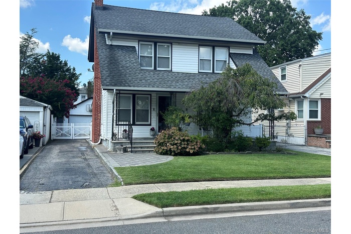 Traditional home featuring roof with shingles, an outbuilding, a chimney, and covered porch