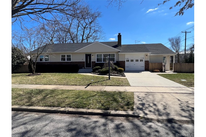 Ranch-style house with a chimney, brick siding, driveway, a garage, and roof with shingles