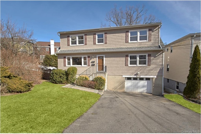 Traditional-style home with an attached garage, driveway, and a front yard