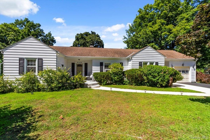 Ranch-style house with an attached garage, a front yard, and asphalt driveway