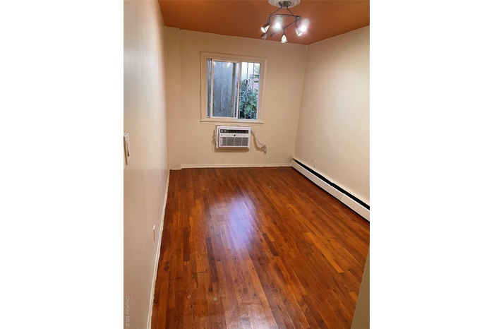 Spare room featuring dark wood-style flooring and baseboard heating