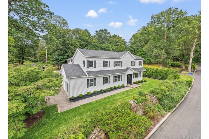 View of front of property featuring a shingled roof, a front yard, and view of scattered trees
