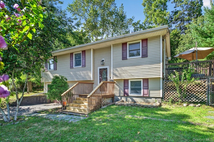 Split foyer home with a front lawn and a wooden deck