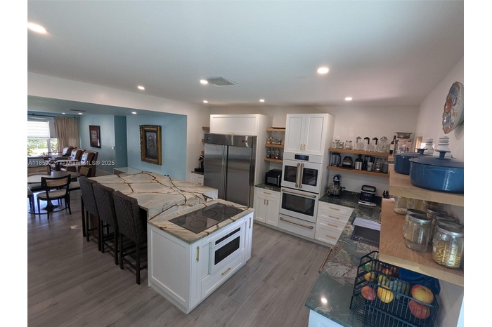 Luxurious kitchen with high ceiling, accented by designer recessed lighting and appliances matching the cabinetry that complement the space beautifull