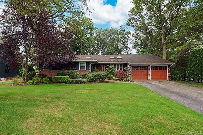 Ranch-style home featuring a front yard, a garage, and asphalt driveway