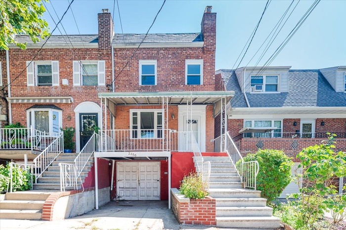 View of front of home with stairway, brick siding, a chimney, and an attached garage