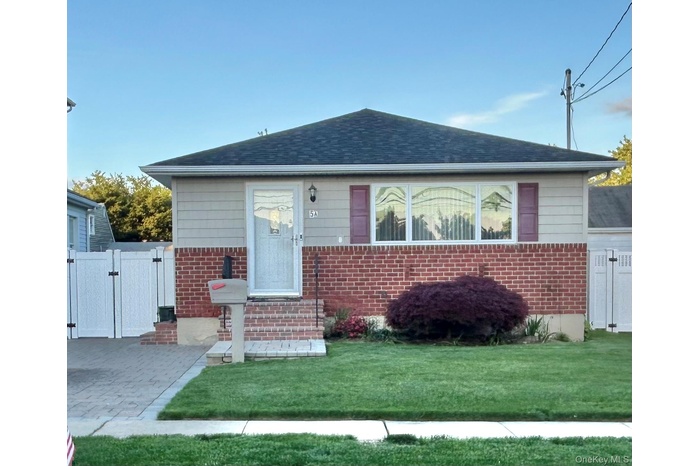 View of front of property featuring a gate, brick siding, and a shingled roof
