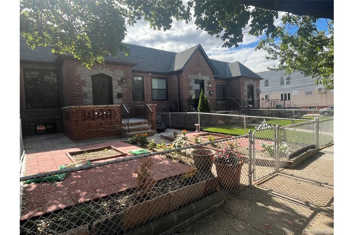 English style home with a gate, a fenced front yard, brick siding, and a patio area