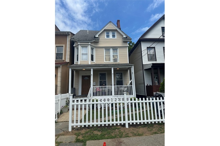 View of front of property with a porch, a chimney, and a fenced front yard