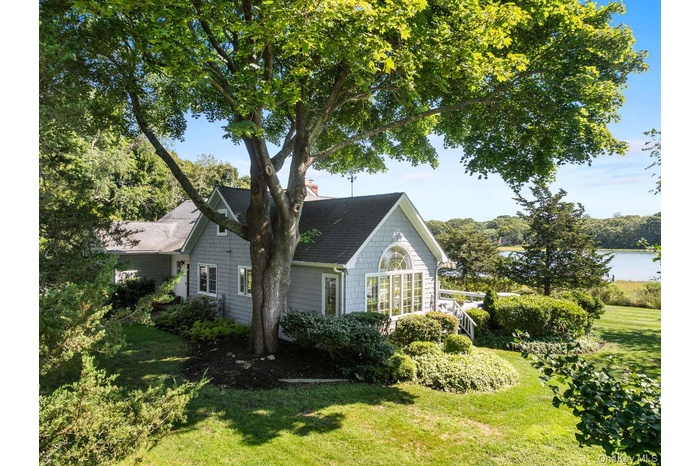 View of property exterior with a lawn, a shingled roof, and a water view