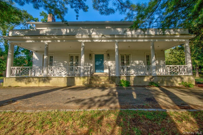 View of front of home with a porch, a chimney, and french doors