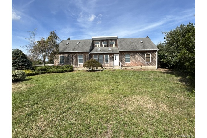 Back of house with a lawn and roof with shingles