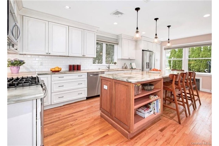 Kitchen featuring a wealth of natural light, light hardwood / wood-style floors, a kitchen island, and appliances with stainless steel finishes