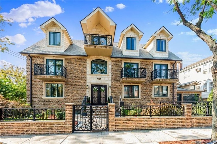 View of front of home with a balcony, a fenced front yard, french doors, and brick siding