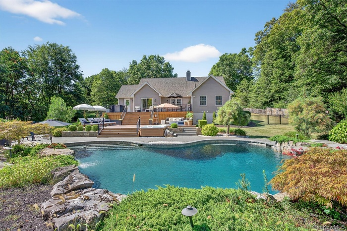 Swimming pool featuring a wooden deck, a patio, and view of wooded area