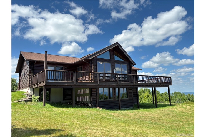 Rear view of property with a wooden deck and a yard