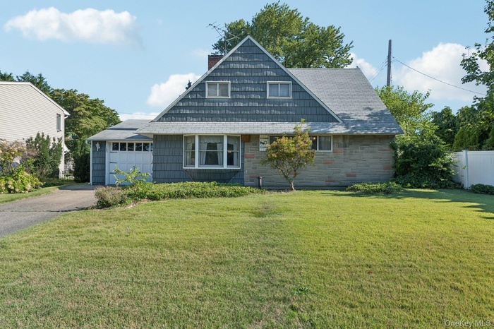 View of front of property with driveway, a chimney, a garage, stone siding, and roof with shingles