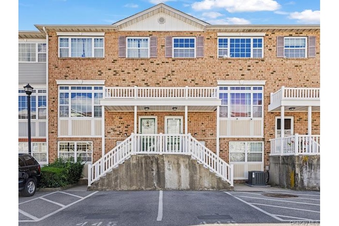 View of building exterior featuring stairs and uncovered parking